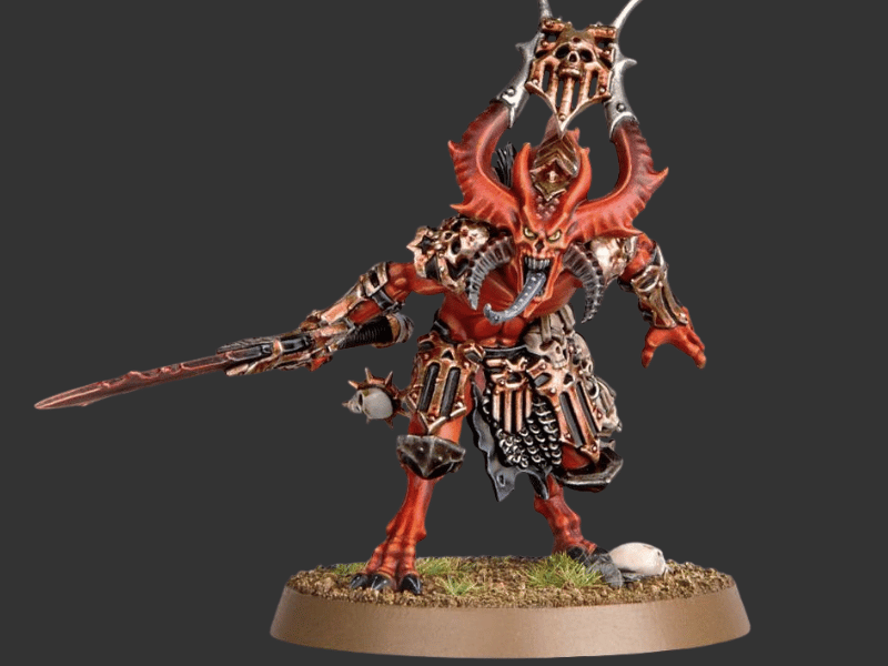 A painted fantasy miniature figurine of a skeletal demon or grim reaper-like warrior on a round base, shown against a dark gray studio background. The figure has red skin, black and silver armor, a large skull-like helmet, and holds a sword.