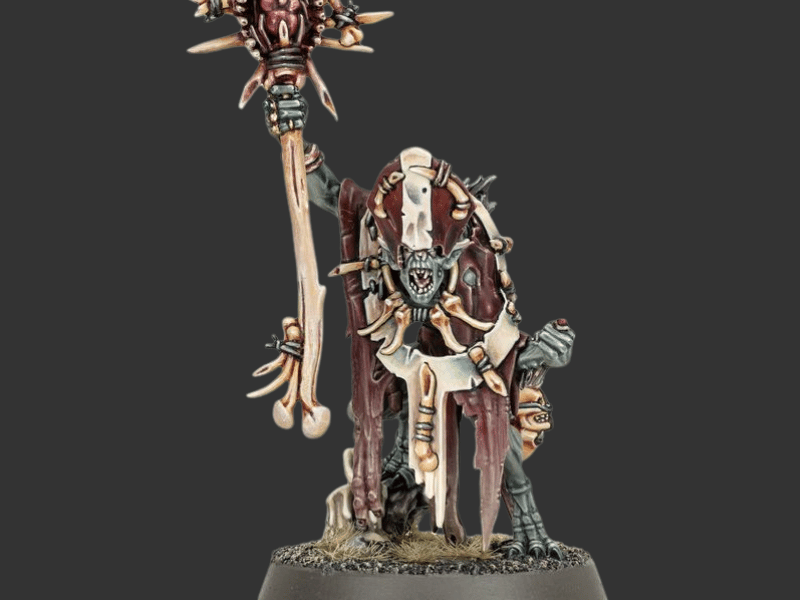 A painted fantasy miniature figurine of a skeletal warrior holding a large mace, standing on a circular base against a dark gray background.