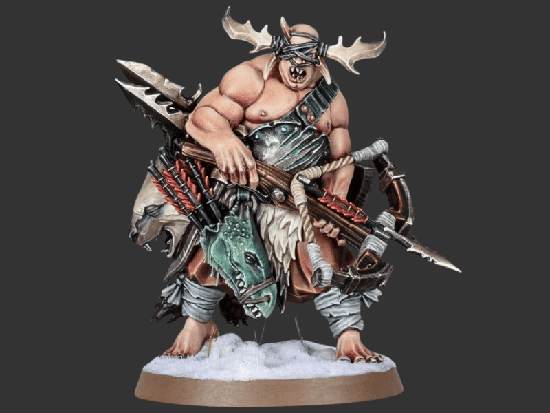 A painted fantasy warrior miniature figure with muscular build, antlered headband, dark armor, and a large bow and crossbow, standing on a snowy round base against a dark gray background.