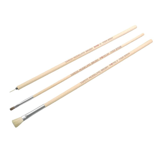Three paint brushes with wooden handles on a white background