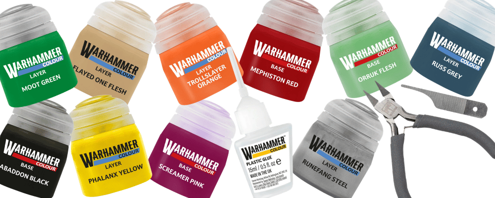 A set of Warhammer 40k miniature paint bottles in various colors, arranged alongside a pair of metal tweezers on a plain white background.