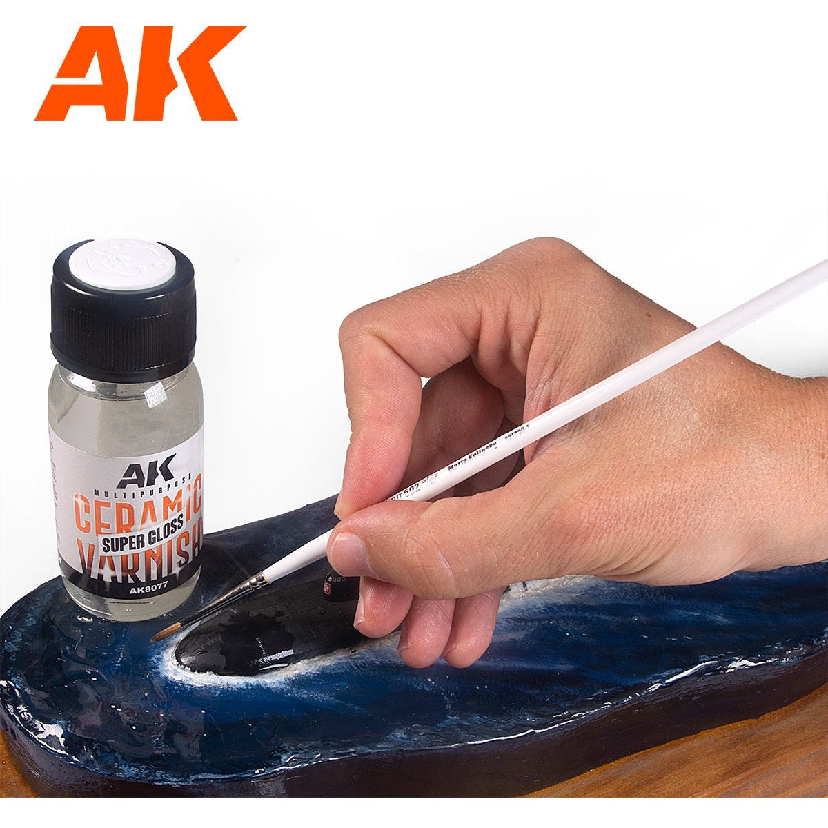 AK Interactive Ceramic Varnish 60ml bottle beside a hand brushing gloss varnish onto a water effect