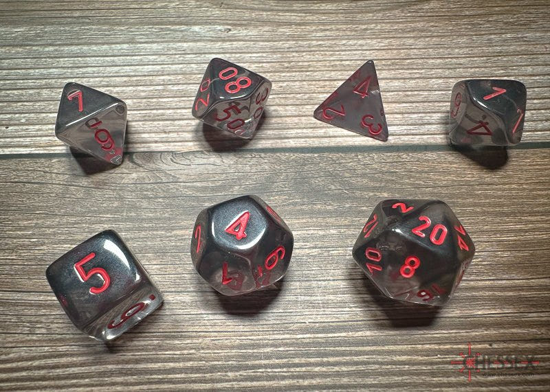 Chessex Translucent Smoke and Red dice laid out on a wooden table, all seven dice