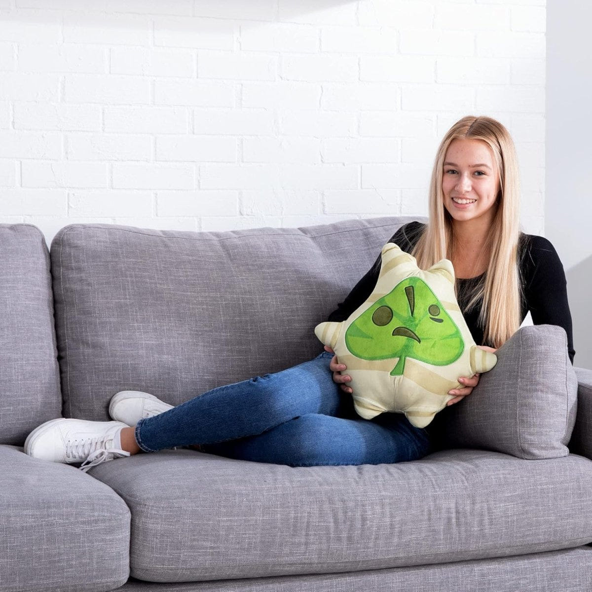 Woman relaxing on a sofa hugging the Club Mocchi-Mocchi Korok plush