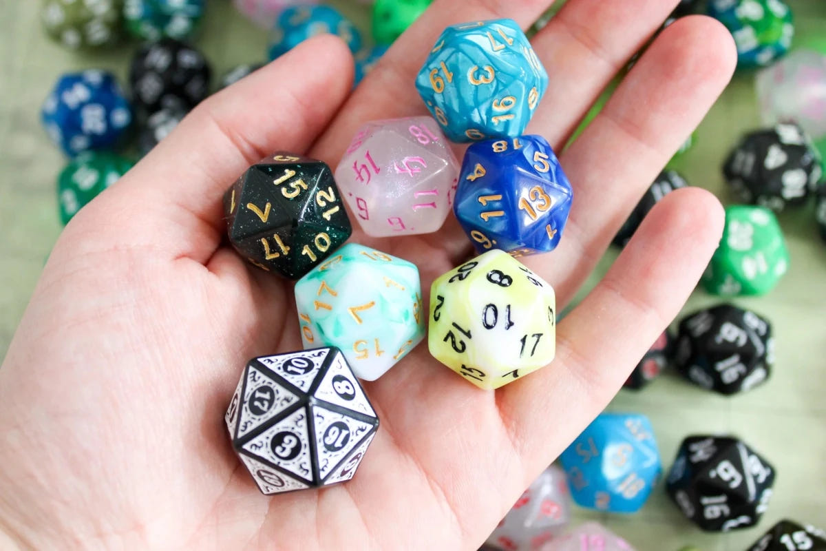 Hand holding a mix of seven random D20 dice from the Dice Goblin bundle bag