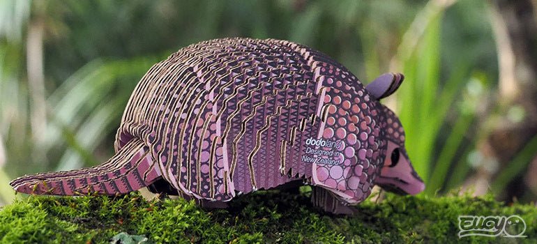 EUGY Armadillo card model on moss, rear three-quarter view against greenery