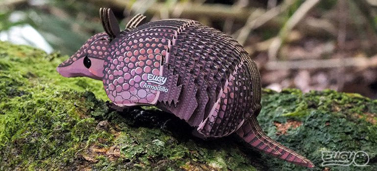 Finished EUGY Armadillo card model on a mossy log outdoors