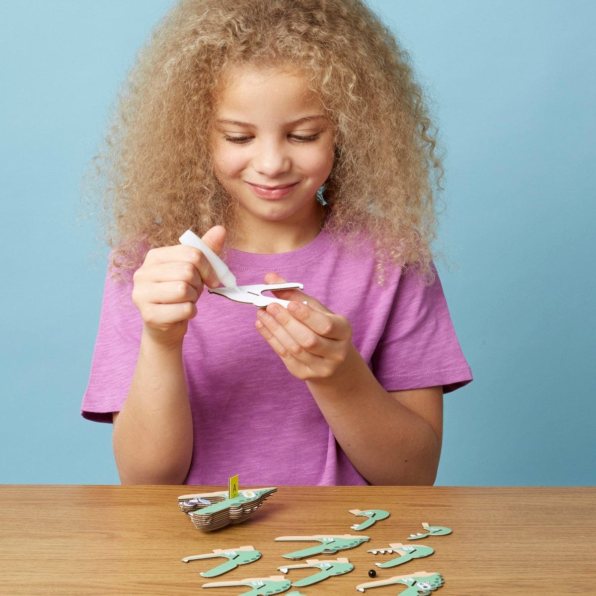 EUGY Crocodile 3D cardboard model kit - child gluing the pieces
