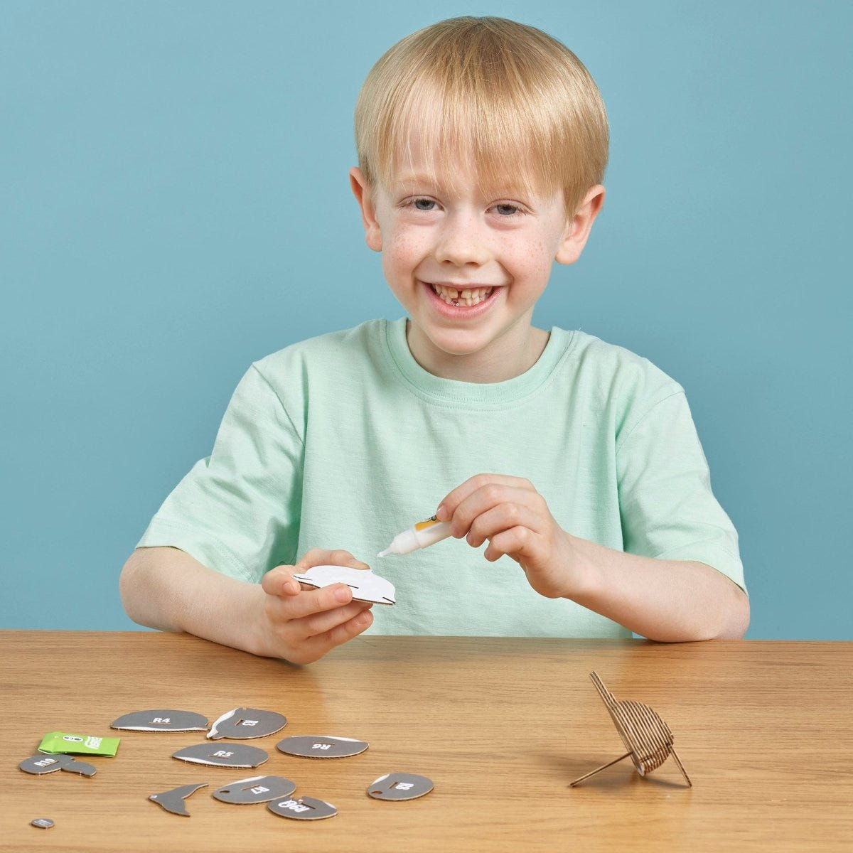 EUGY Dolphin 3D cardboard model kit - child gluing the pieces