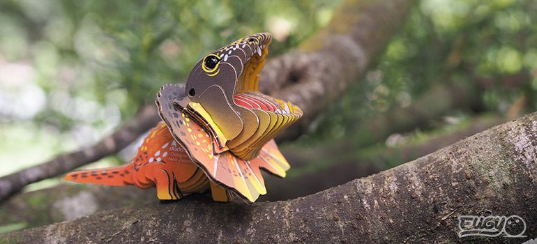 Finished EUGY Frilled Lizard card model perched on a tree branch outdoors