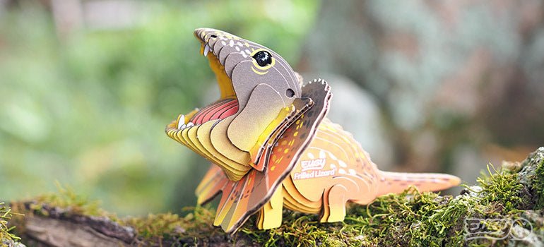 Finished EUGY Frilled Lizard card model on a mossy log with its frill raised