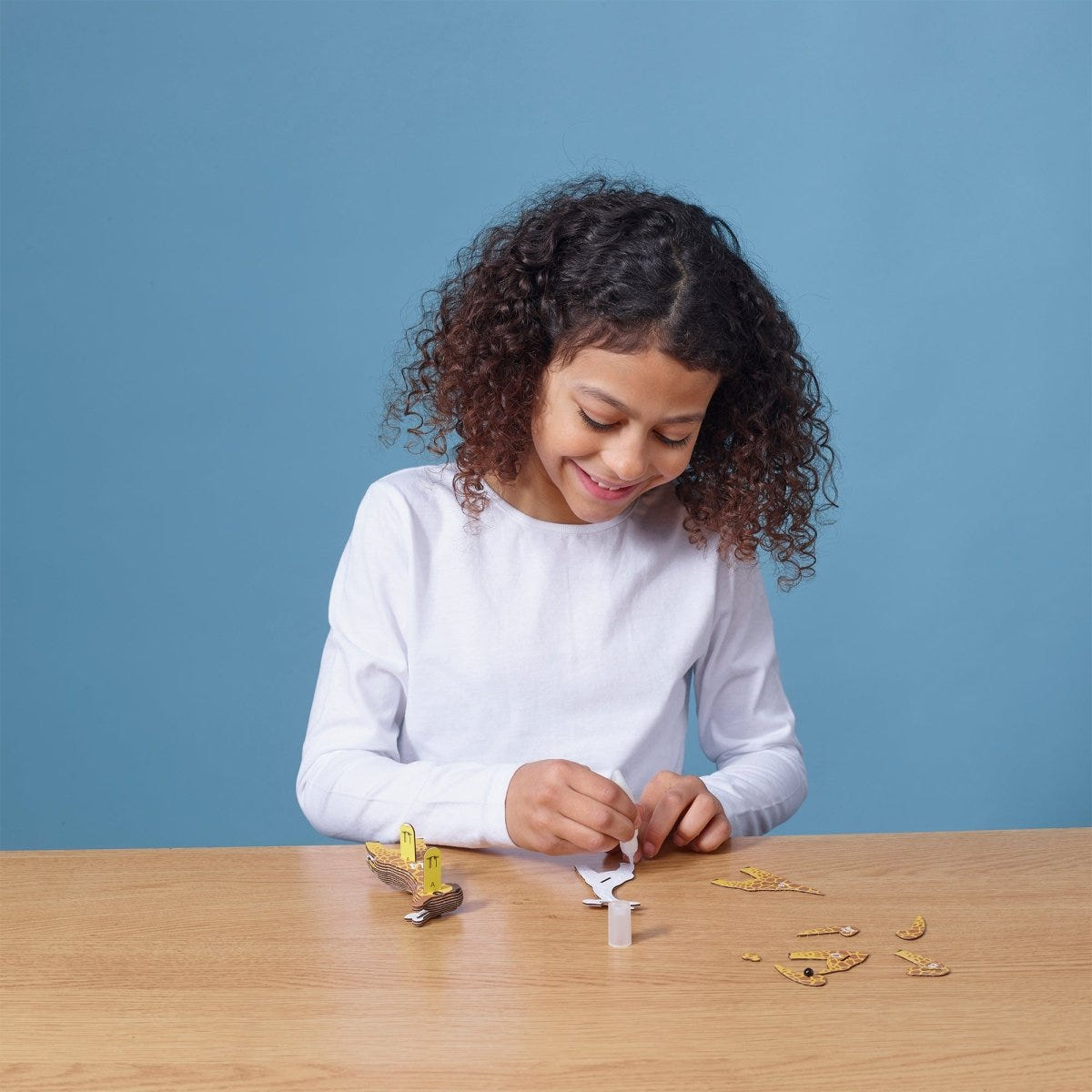 EUGY Giraffe 3D cardboard model kit - child gluing the pieces