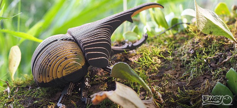 Finished EUGY Hercules Beetle card model posed on moss among forest plants