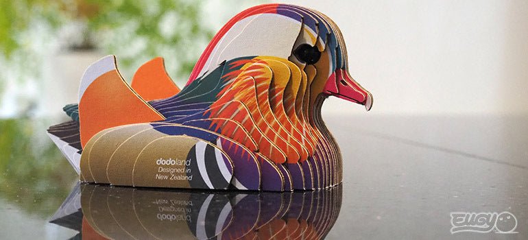 Finished EUGY Mandarin Duck card model on a glossy table, rear three-quarter view