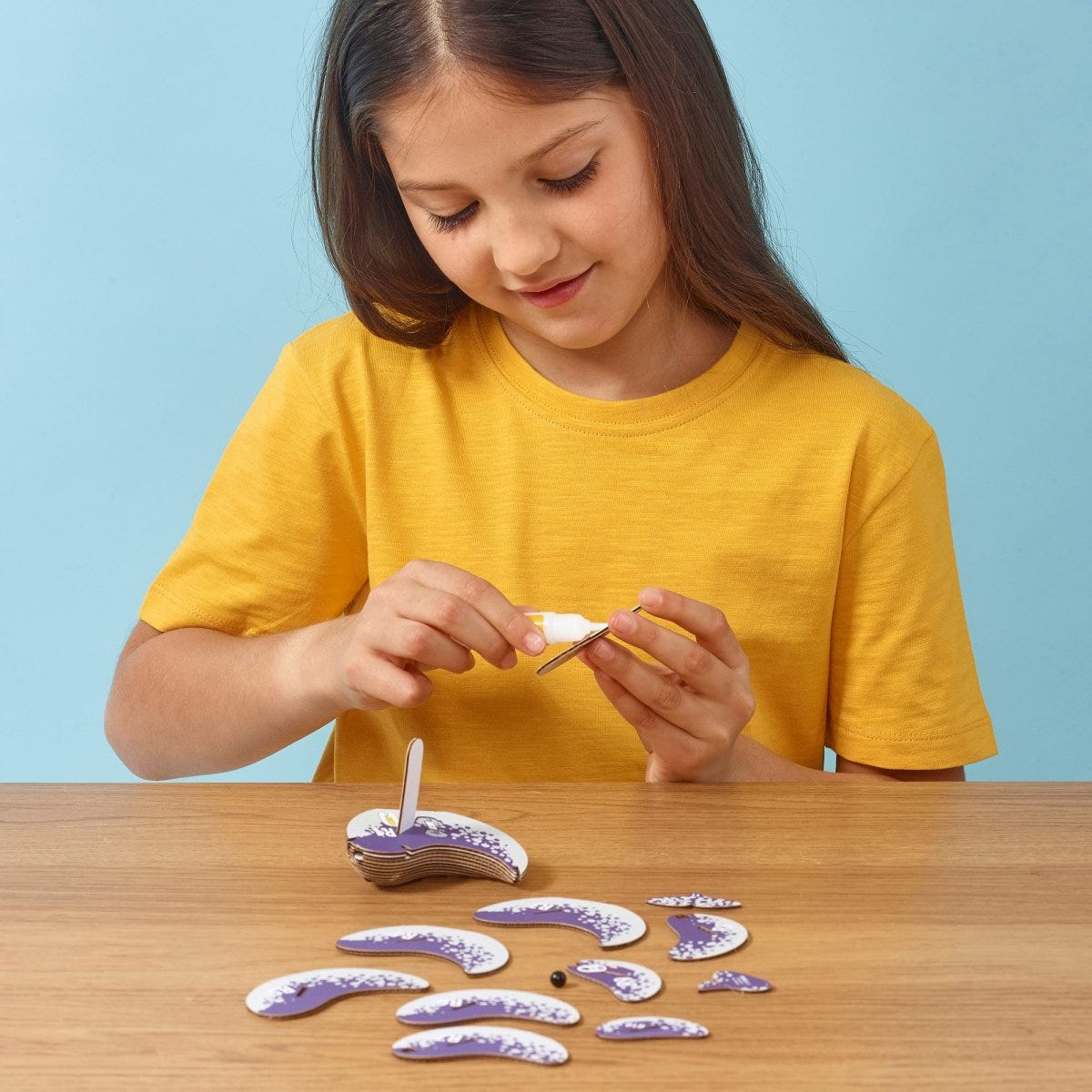 EUGY Narwhal 3D cardboard model kit - child gluing the pieces