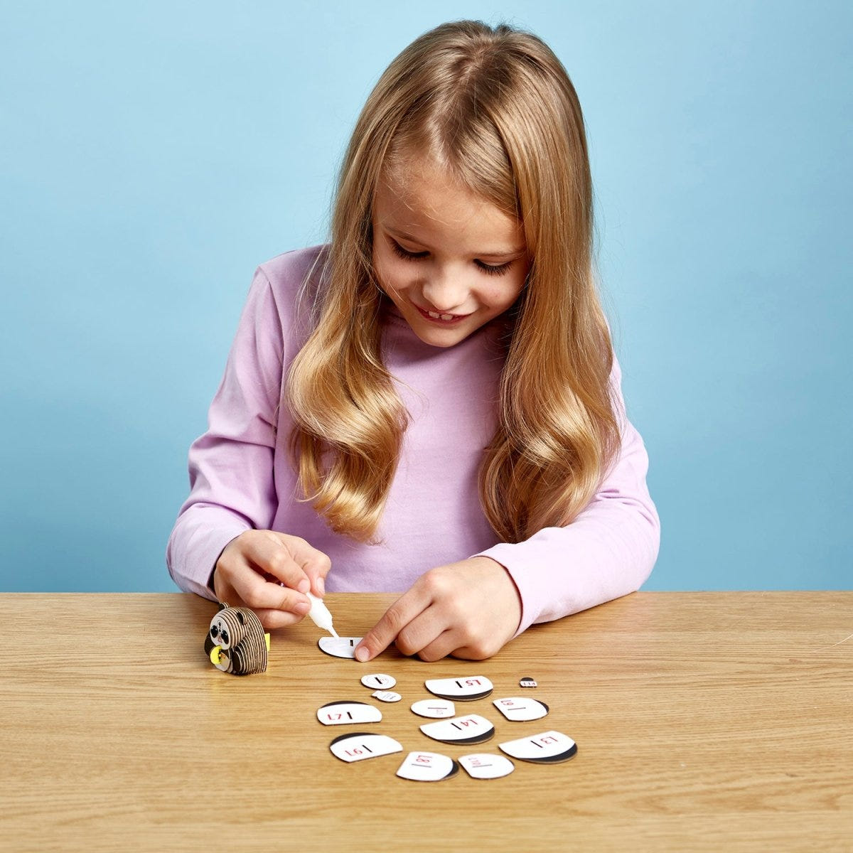 EUGY Panda 3D cardboard model kit - child gluing the pieces