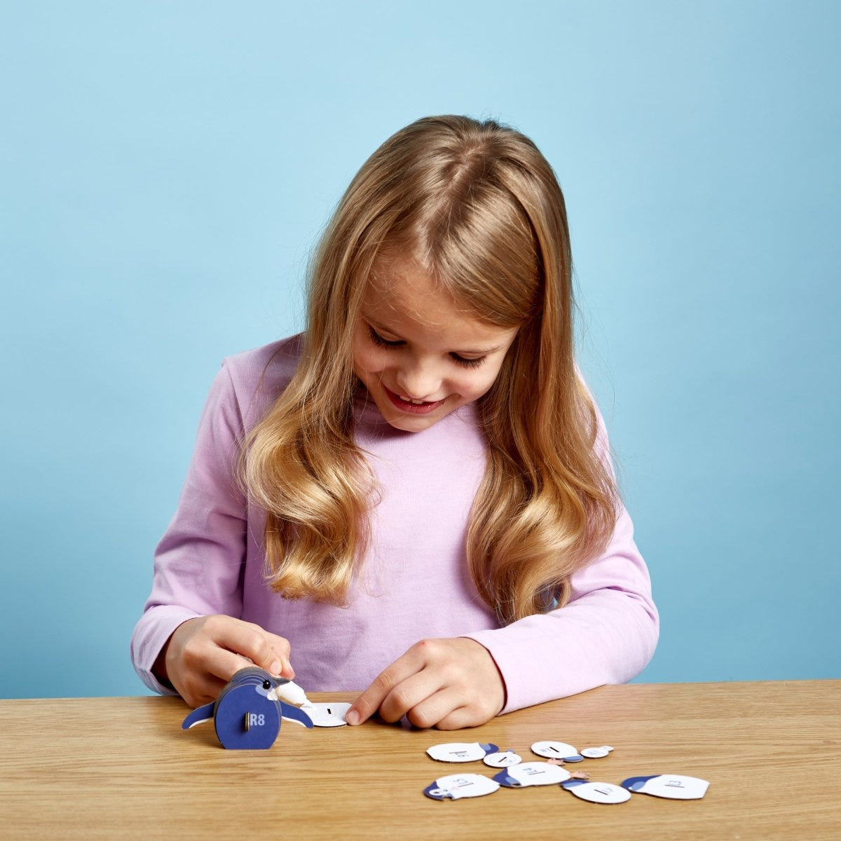 EUGY Penguin 3D cardboard model kit - child gluing the pieces