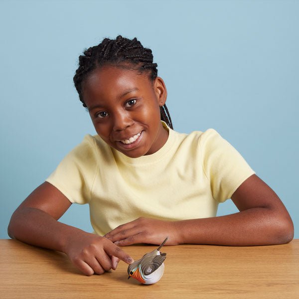 Smiling girl at a table with her finished EUGY Robin card model