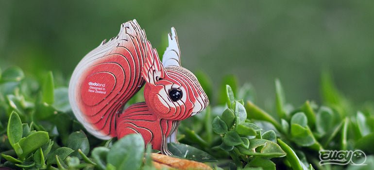 EUGY Squirrel card model sitting among green leaves in an outdoor lifestyle shot