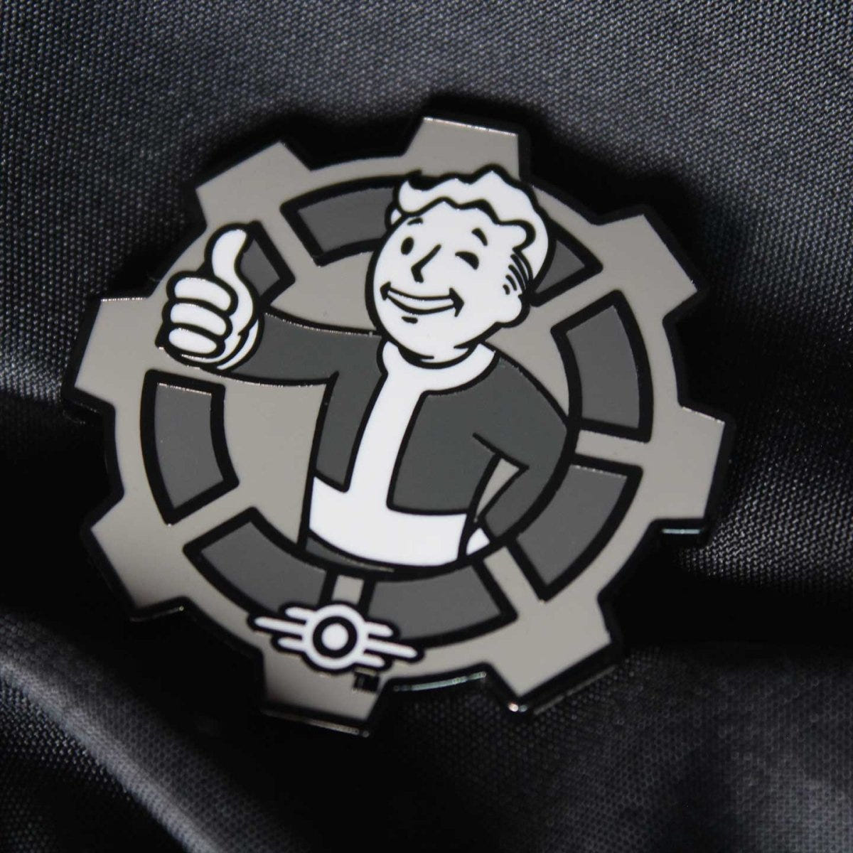 Close-up of the Fallout Decision Coin thumbs-up Vault Boy side on dark fabric