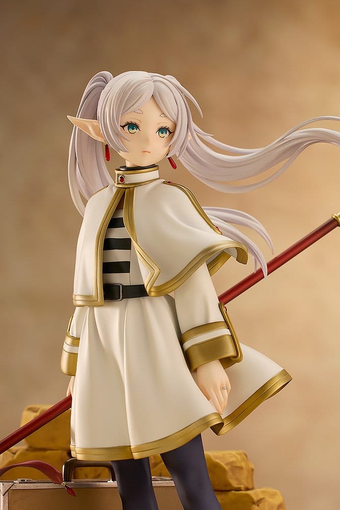 Close-up of Frieren figure's face, twin tails and white cloak on warm brown background