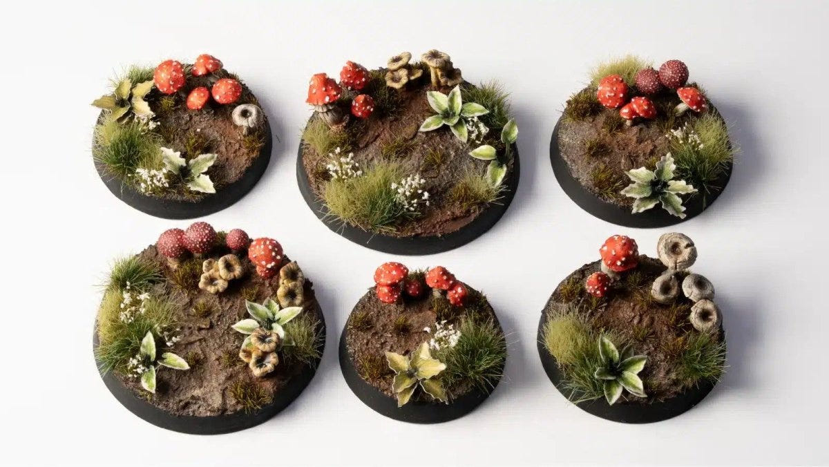 Six round miniature bases decorated with painted Gamers Grass forest mushrooms and plants