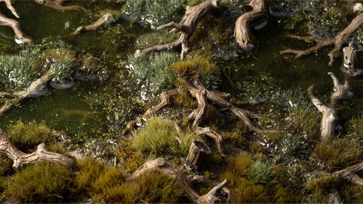 Gamers Grass Gnarled Branches painted and scattered among grass tufts on a woodland board