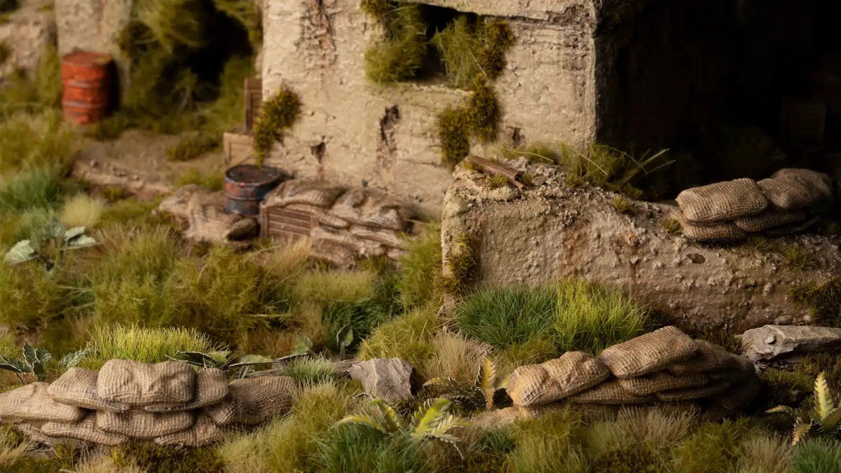 Painted Gamers Grass sandbag barricades set among grass and ruins on a wargaming terrain board