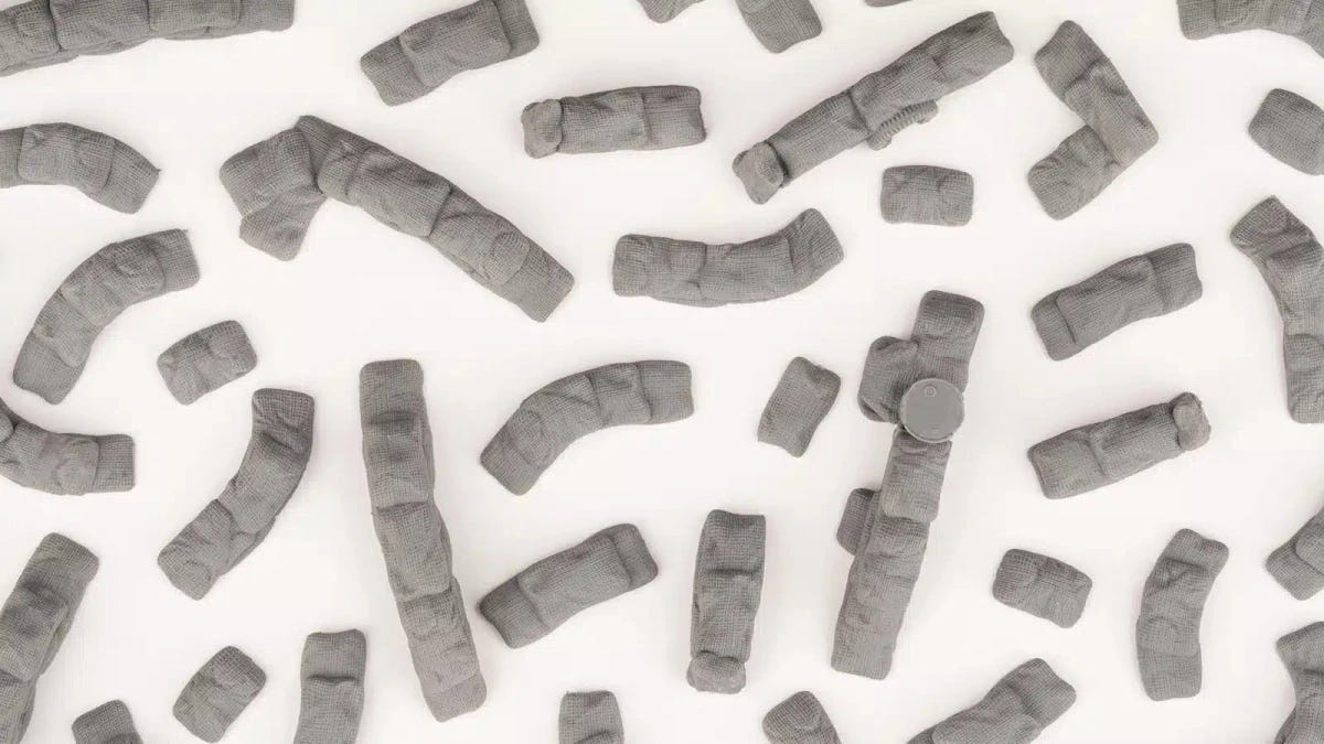 Loose unpainted Gamers Grass sandbag barricade basing bits scattered on a white surface