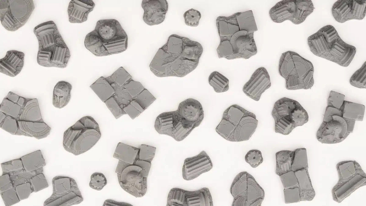 Unpainted Gamers Grass Temple Basing Bits laid out: column fragments, friezes and slabs