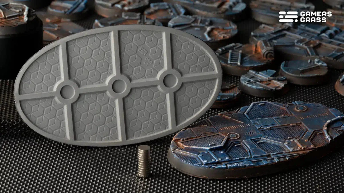 Grey underside of a Gamers Grass Spaceship Corridor oval base with magnet slots, beside painted bases