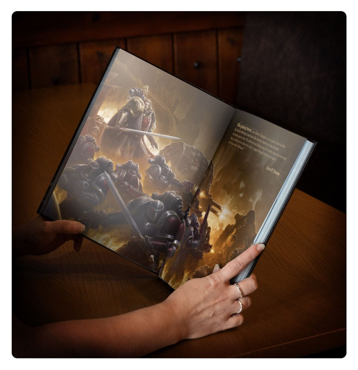 Hands holding Liber Astartes open at a full-page artwork of Space Marine battle