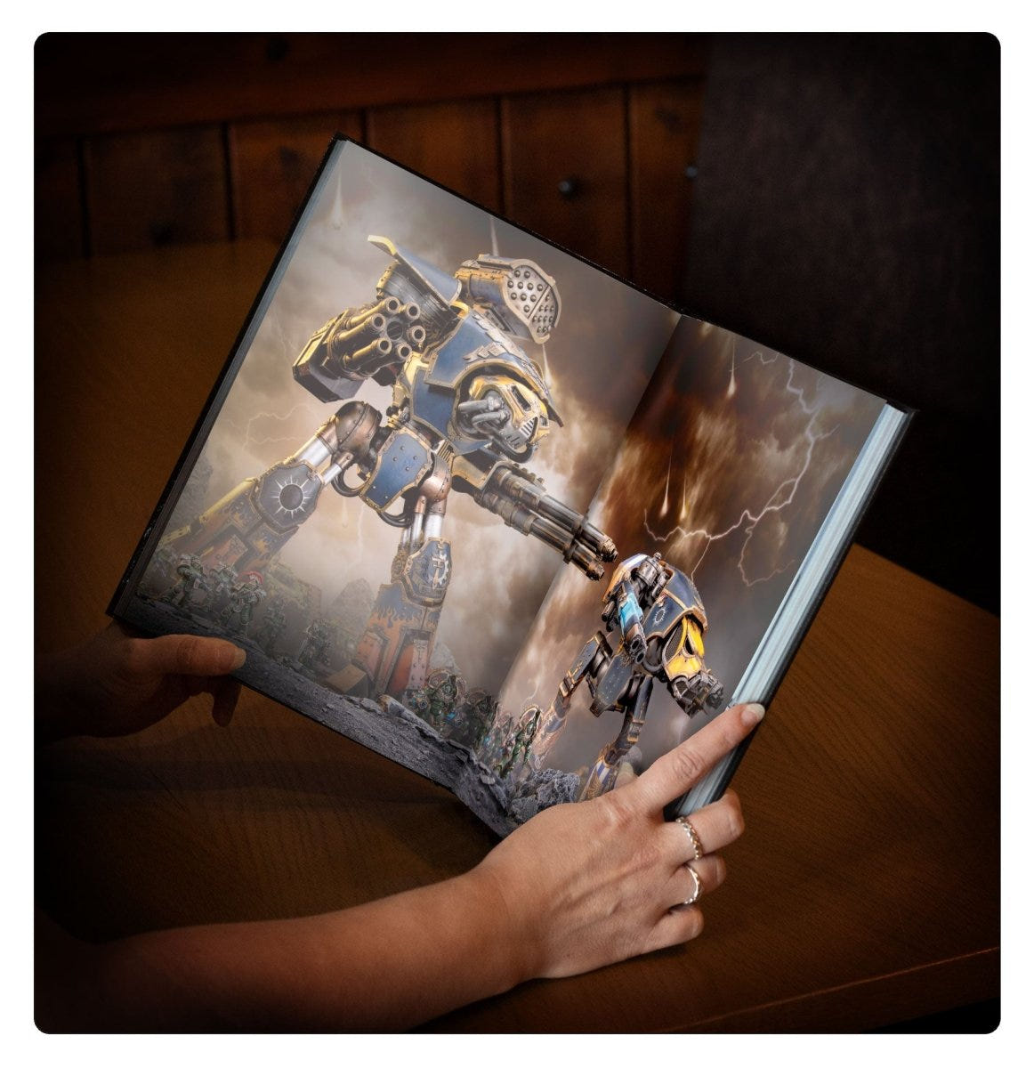 Liber Questoris army book held open at a double-page Imperial Knight battle illustration