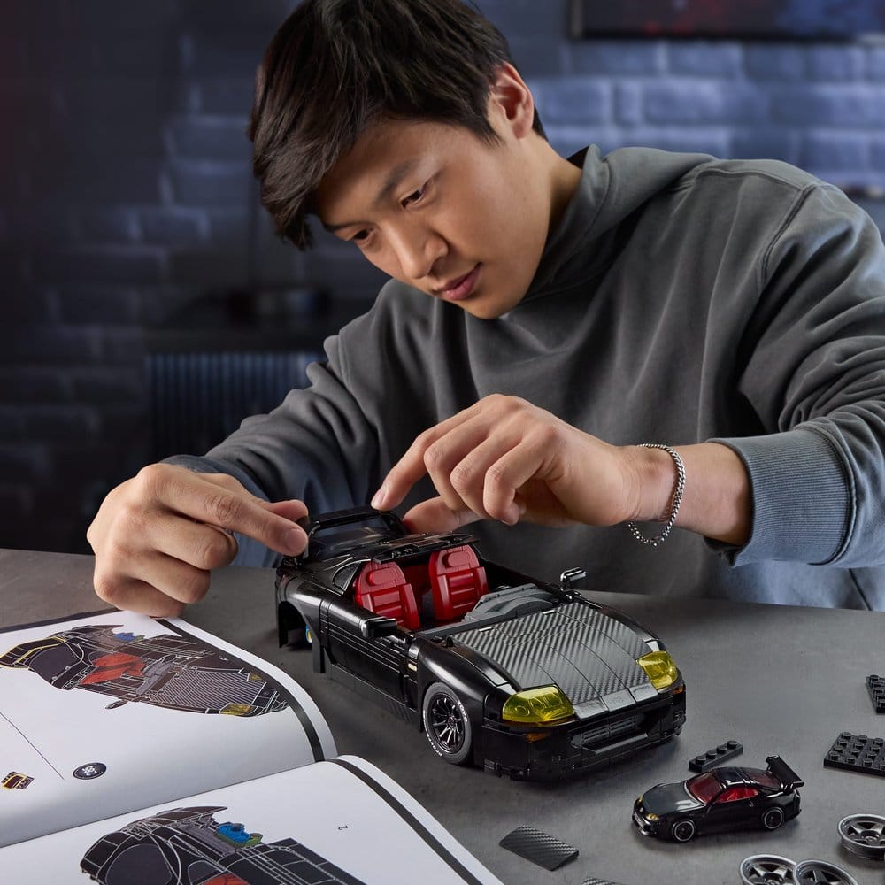 Man building the black Hot Wheels Elite '94 Toyota Supra MKIV brick set at a table