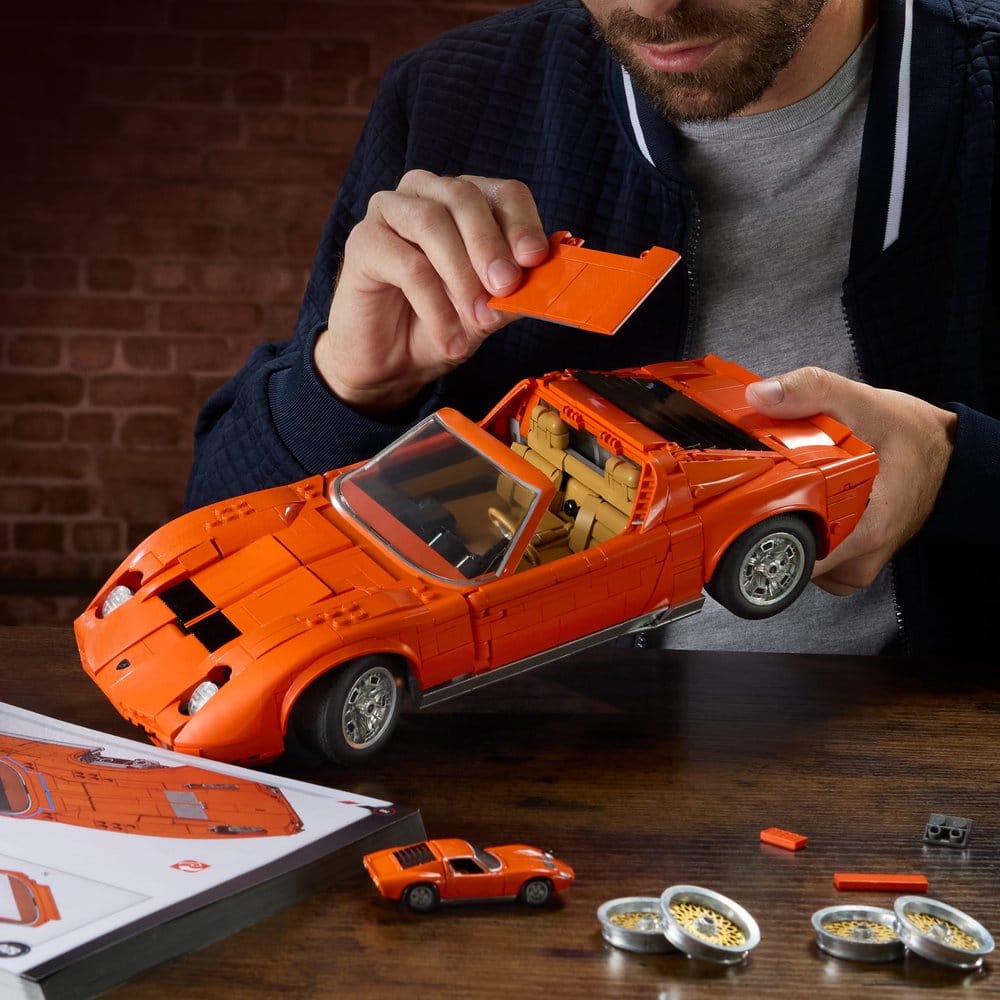 Man fitting parts to the orange Hot Wheels Premium Lamborghini Miura P400 SV brick build
