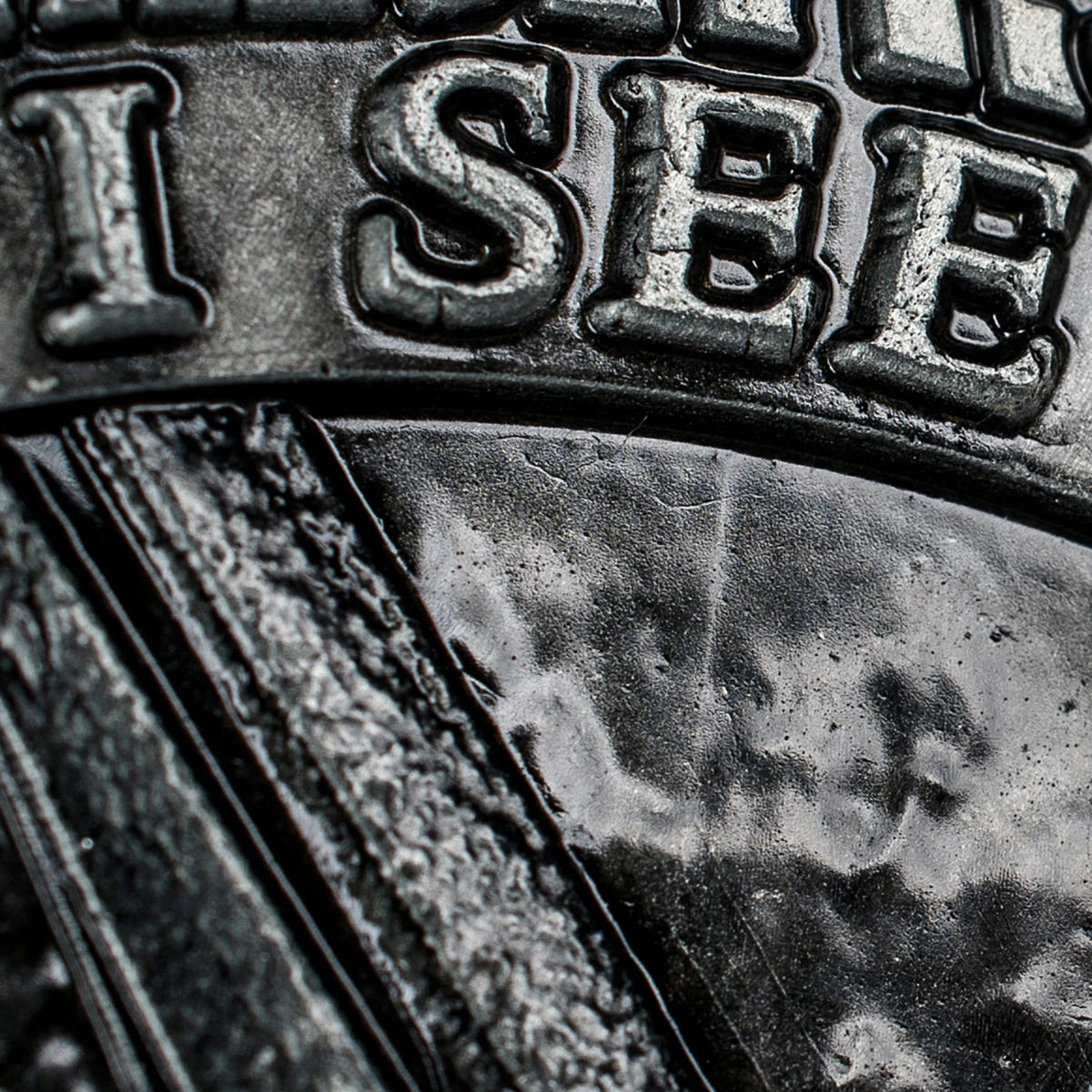 Macro close-up of the raised I SEE lettering on the Sauron side of the coin