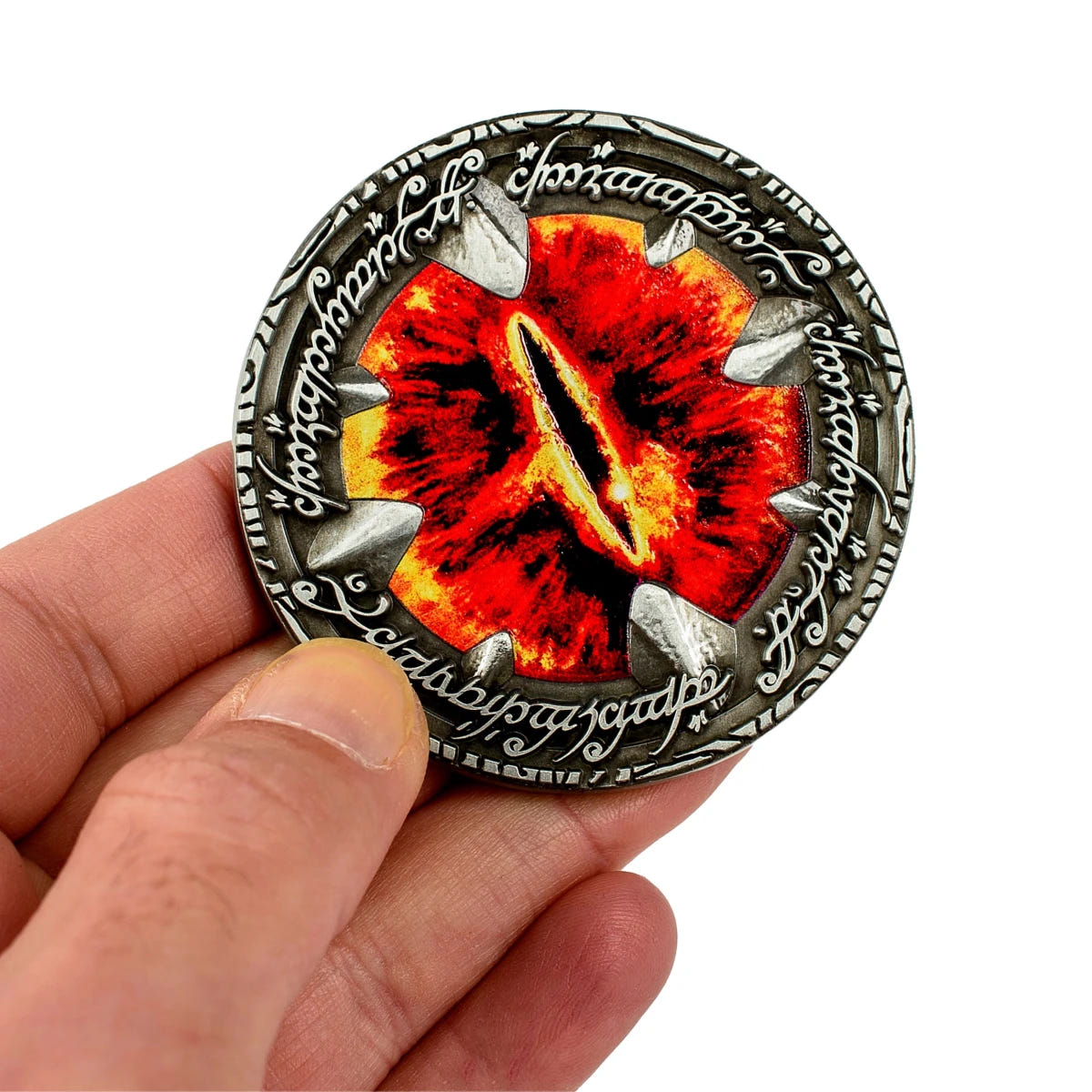 Hand holding the Eye of Sauron Deluxe Coin, enamel eye side angled towards the camera
