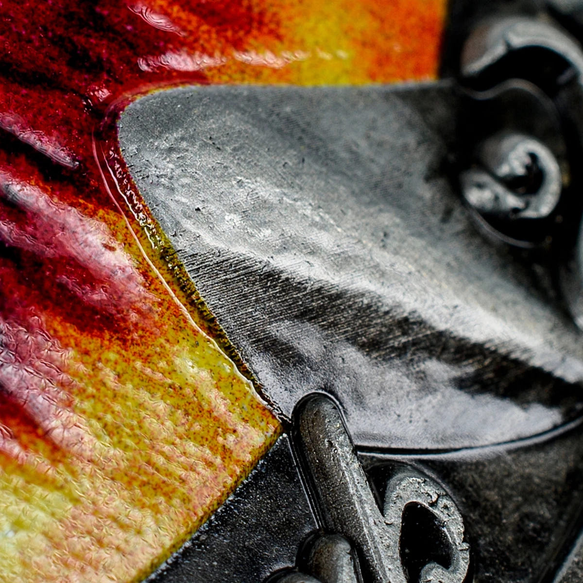 Macro close-up of an antique silver claw over the red enamel of the Eye of Sauron coin