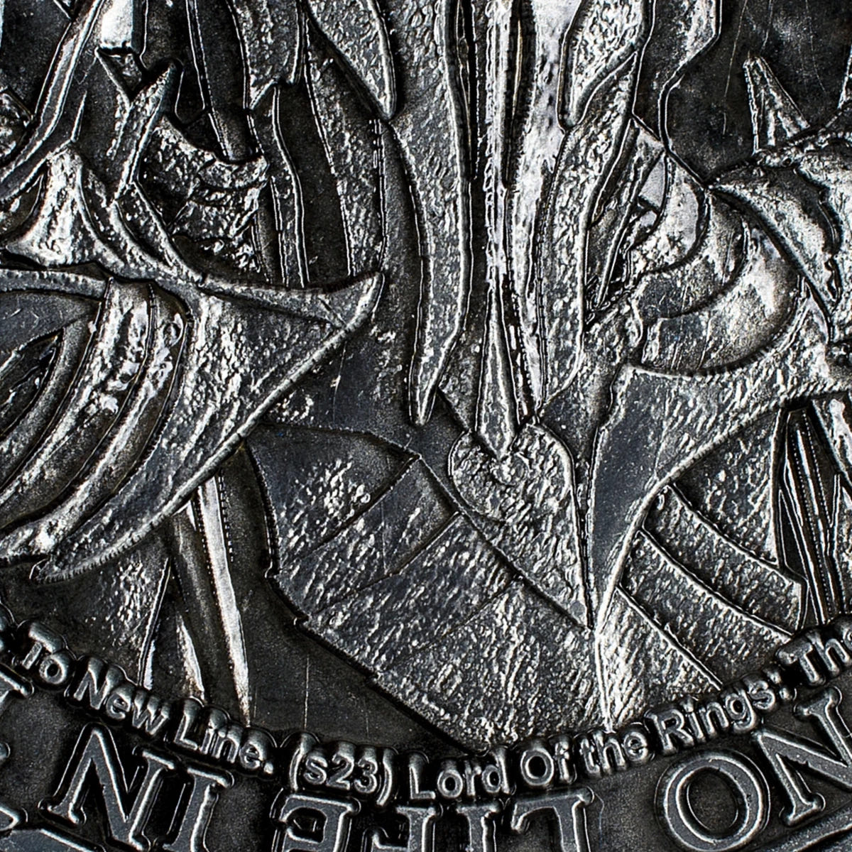 Close-up of Sauron's helm and the inscription text on the coin reverse