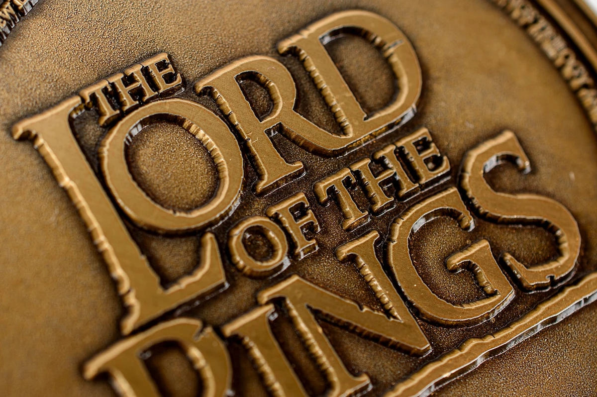 Close-up of the raised Lord of the Rings logo on the bronze-toned coin