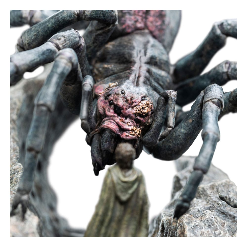 Close-up of Shelob's face and clustered eyes above the hobbit figure