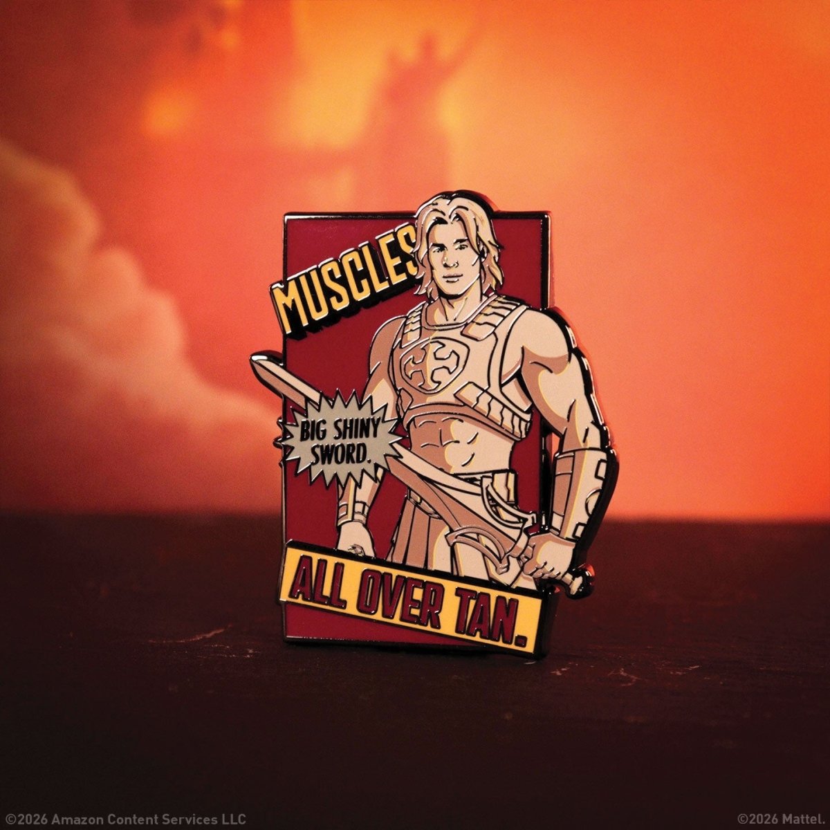 Masters of the Universe He-Man enamel pin badge shown against a sunset background