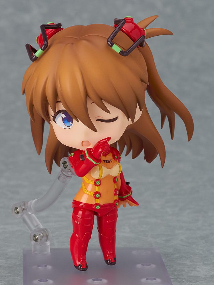 Asuka Test Suit Nendoroid with winking faceplate and hand raised to her mouth, on its clear stand