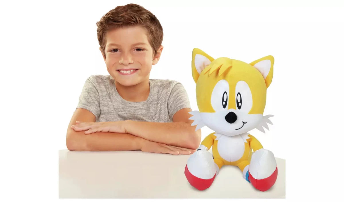 Smiling boy sitting beside the TOMY Tails jumbo plush to show its size