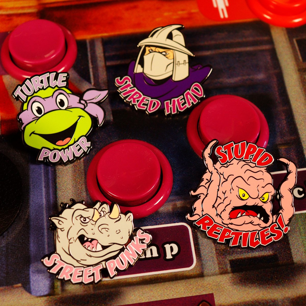 TMNT mystery pin badges of Donatello, Shredder, Rocksteady and Krang among red arcade buttons