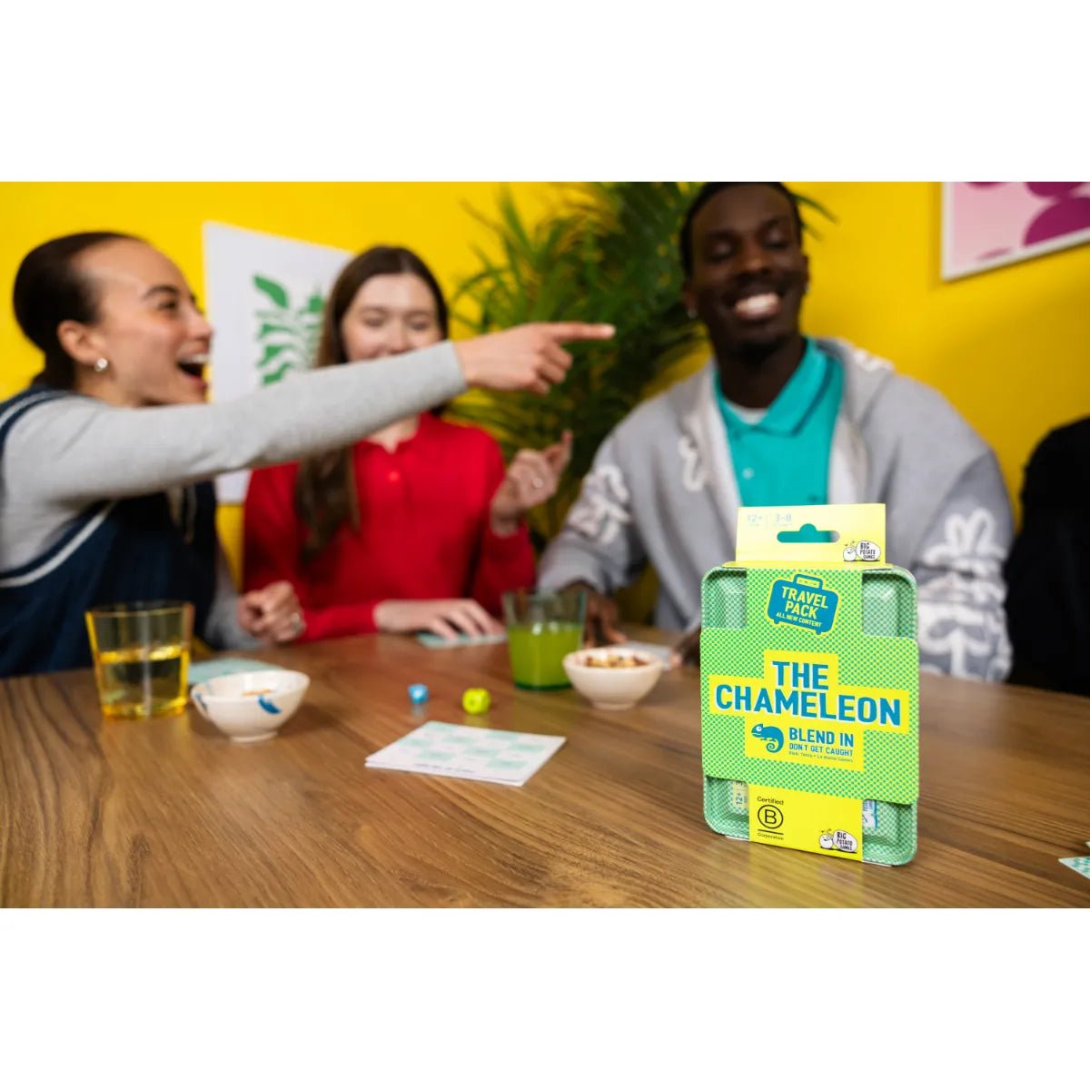 Player pointing at a friend during a game of The Chameleon Travel at a table
