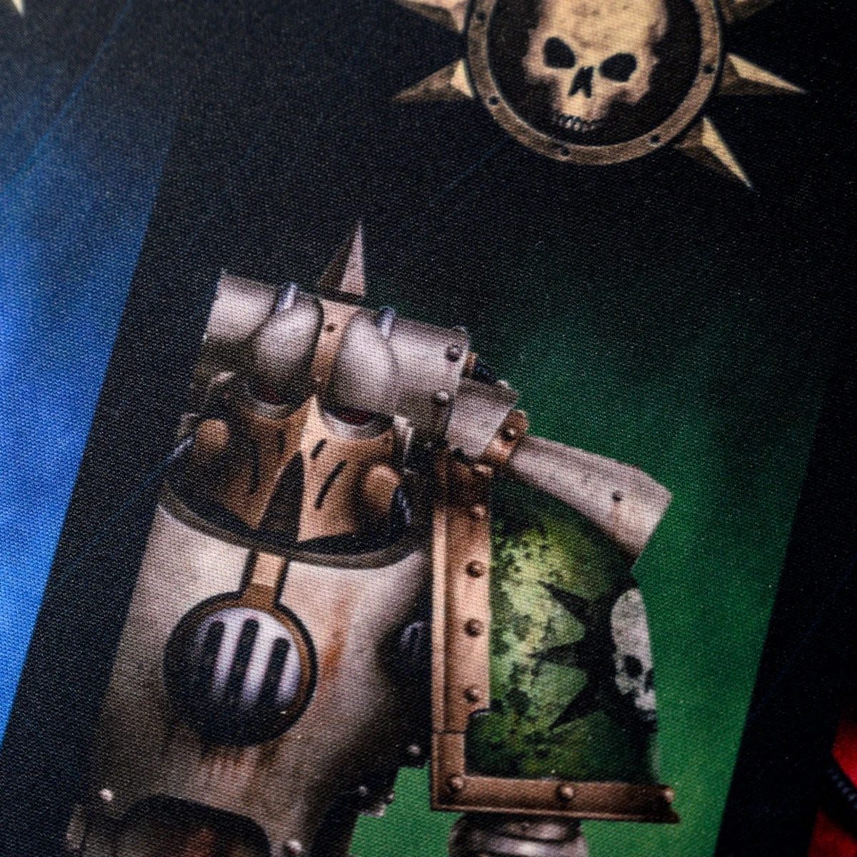 Close-up of a pale armoured Space Marine and spiked skull symbol printed on the Horus Heresy desk mat