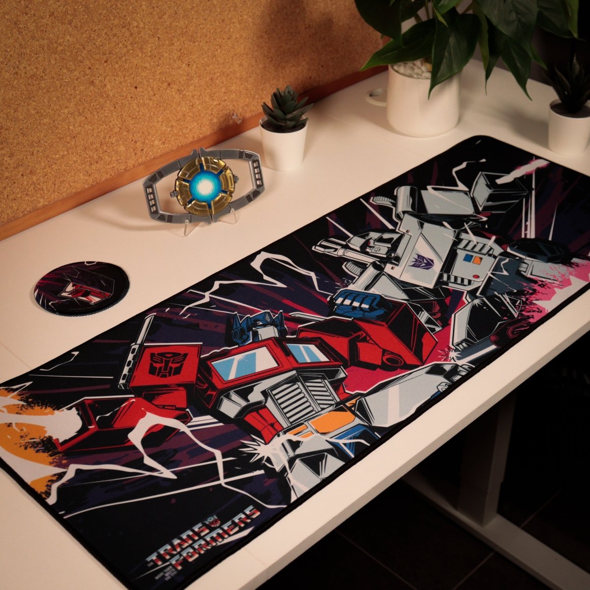 Transformers desk pad and coaster in use on a desk beside plants