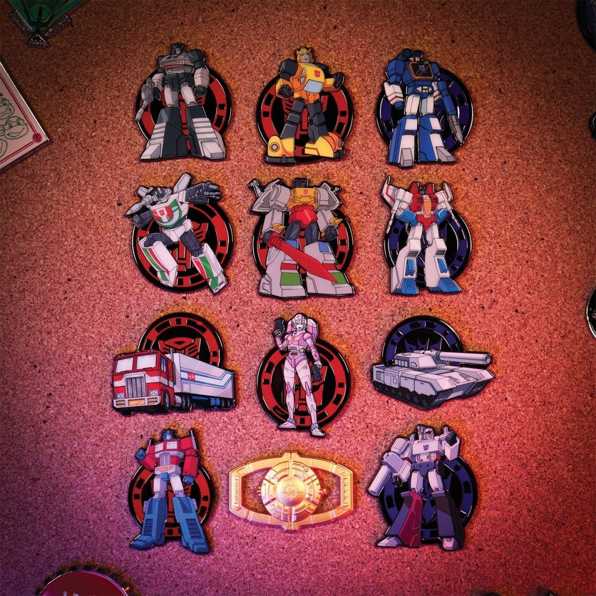 Full set of twelve Transformers mystery pin badges pinned to a cork board