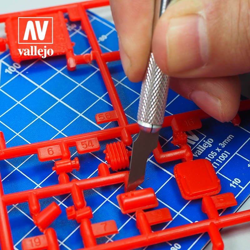 Vallejo hobby knife blade removing parts from a red sprue, close-up of the cut